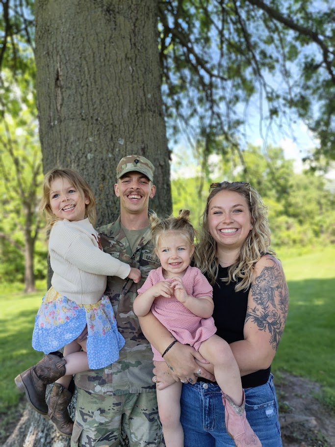 A military family with two young children outdoors